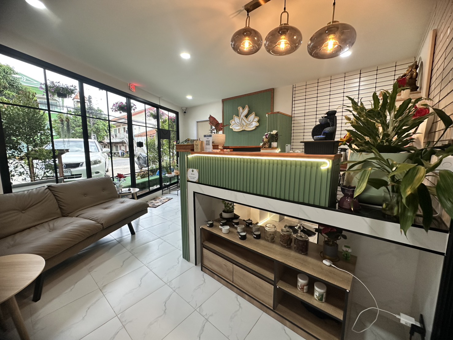 Modern reception area at Ketsirin Cherngtalay with mint green counter, pendant lights, sofa and lotus wall art