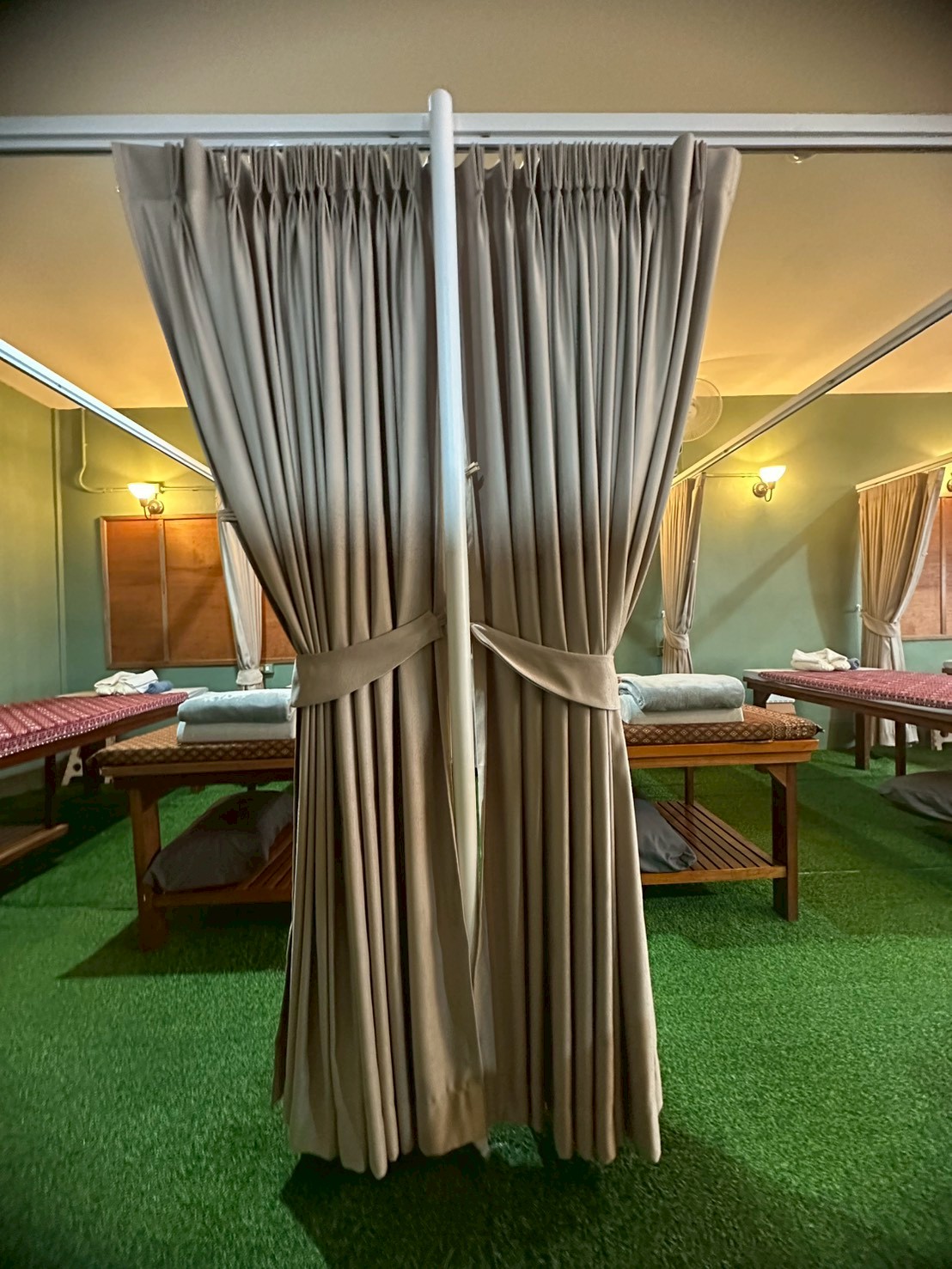 Massage beds with privacy curtains at Ketsirin Wellness Nai Thon in a calm, warm-lit setting